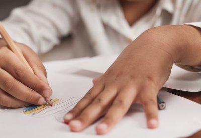 Child drawing on a desk with coloured pencil