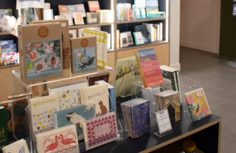Greeting cards, books, and crafting kits on a display case in the Shop
