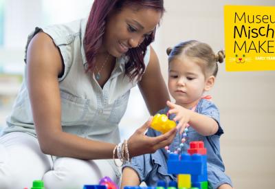 A young woman playing building blocks with a toddler