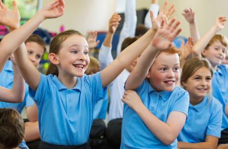 Happy school children raising their hands