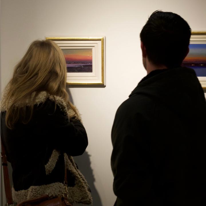 Two visitors looking at impressionist artwork of Sarah Butterfield