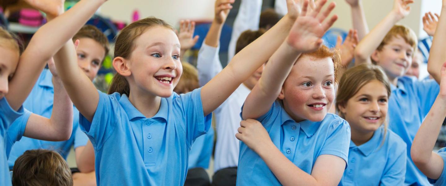 Happy school children with hands in the air